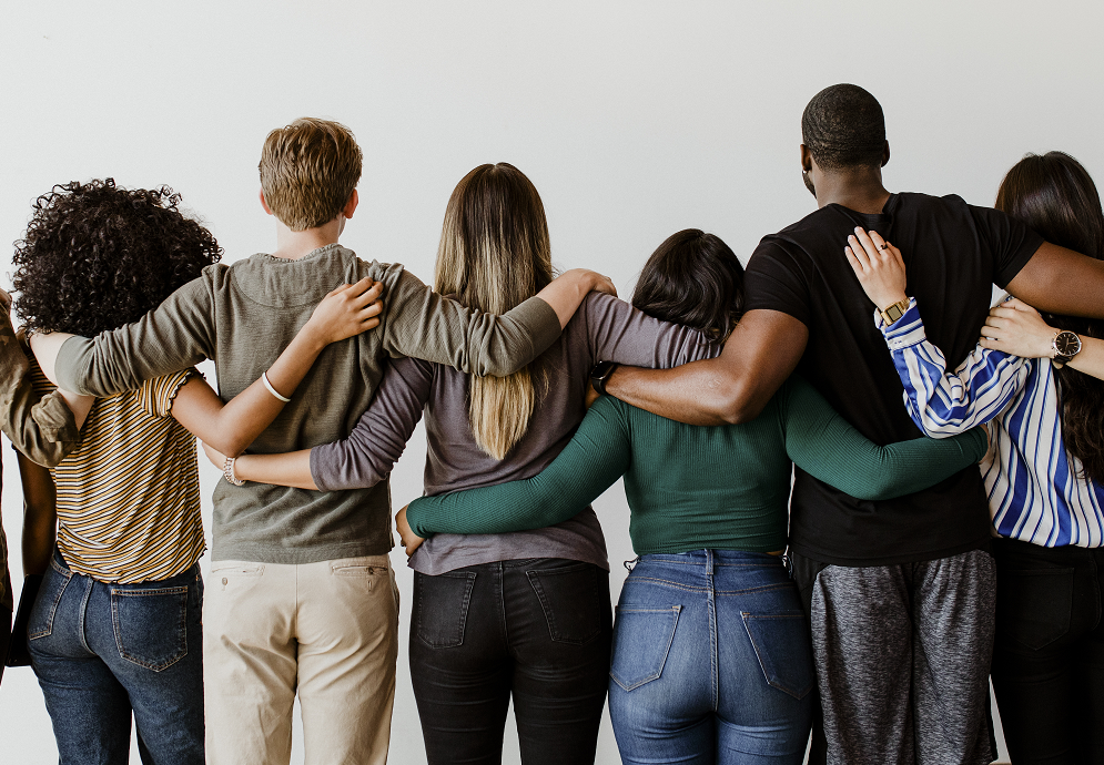 Foto de um grupo diverso de pessoas de costas e em pé abraçadas