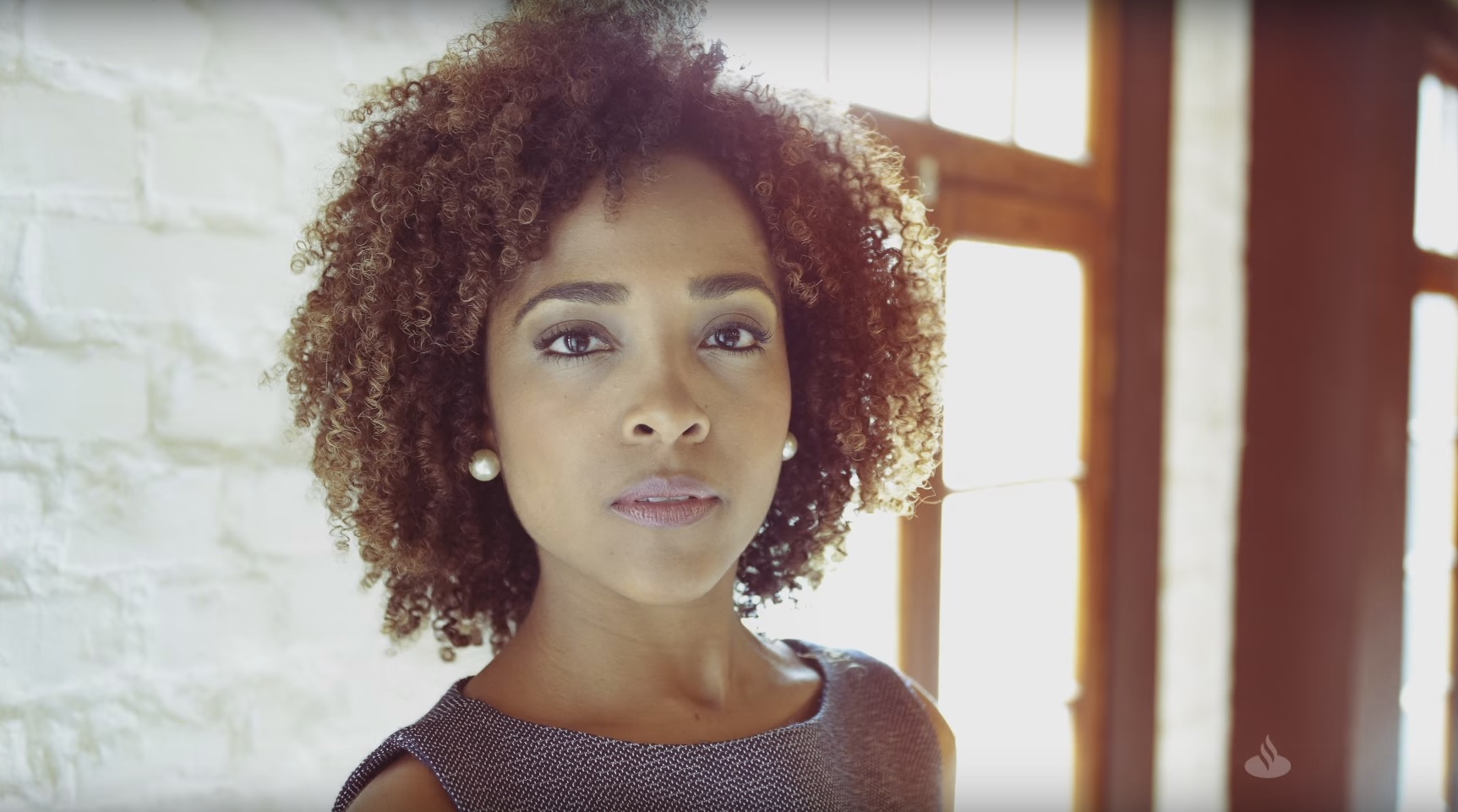 Print da tela do vídeo da nova campanha do Santander. No centro, há a imagem de uma mulher negra.