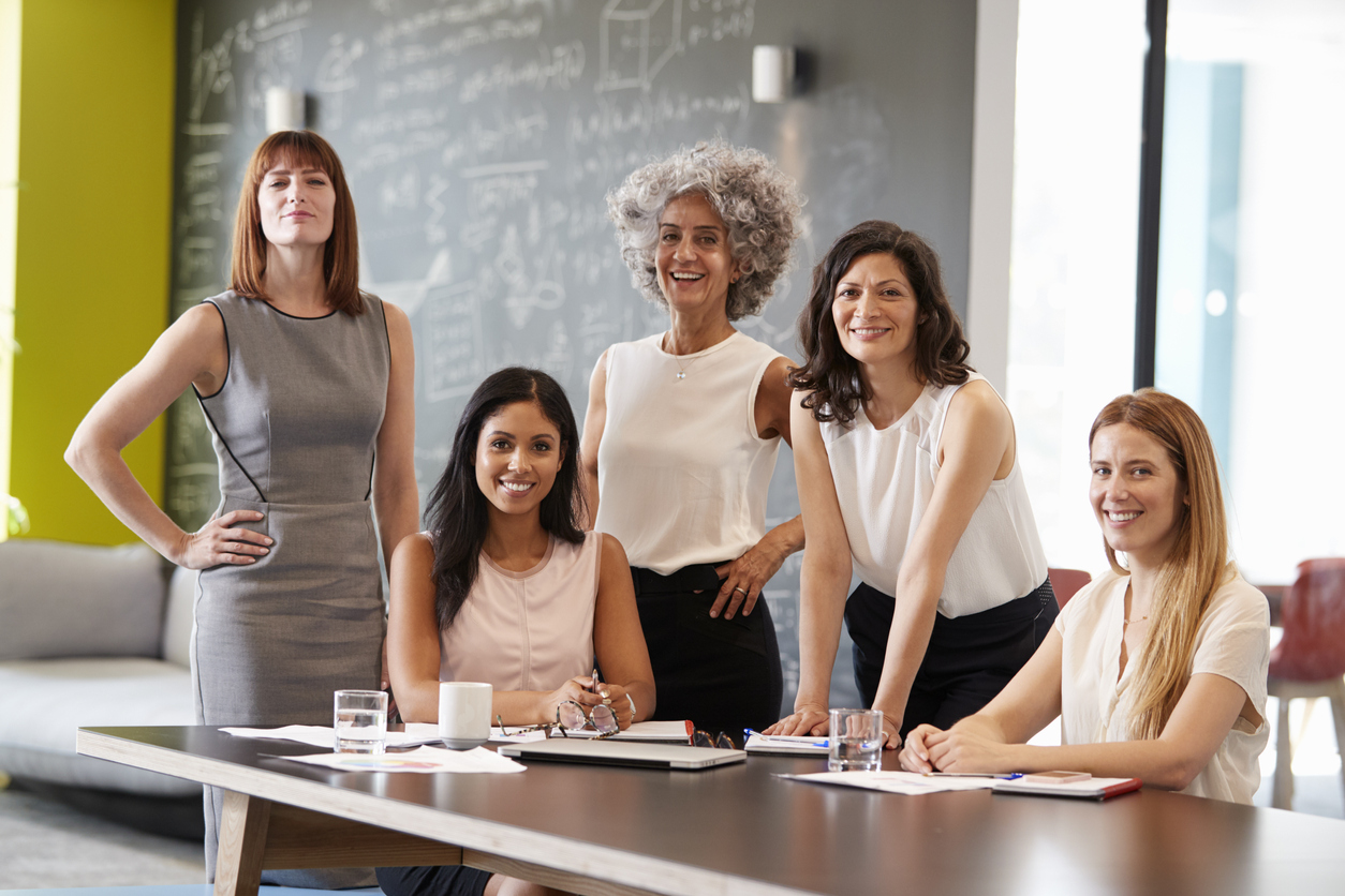 Foto de cinco mulheres em uma sala de reunião.