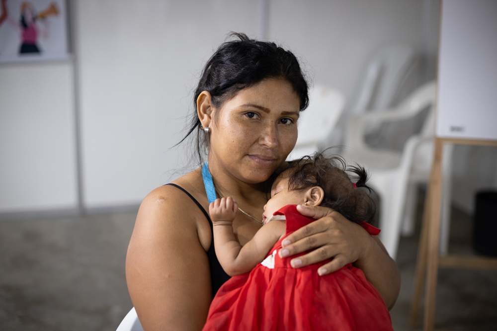 Foto de uma mulher com uma menina no colo.