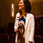 Foto de uma mulher da plateia segurando um microfone.