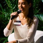 Foto de Silvia Penna falando ao microfone durante sua participação no painel dos CEOs.